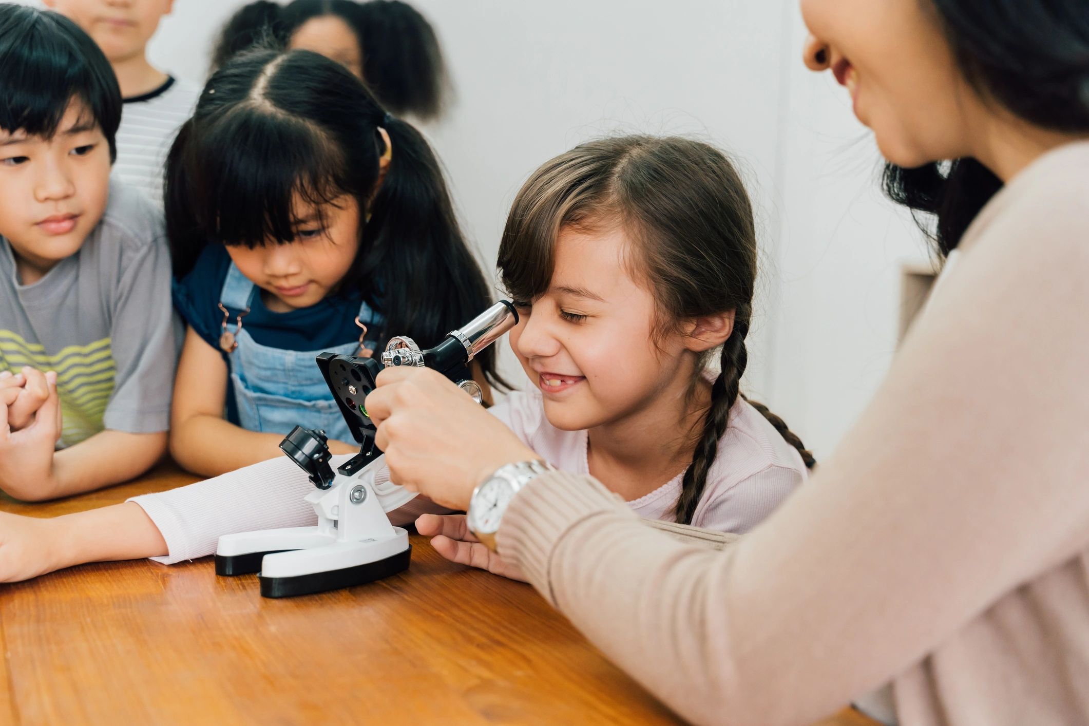 Docente guiando a niños con microscopio
